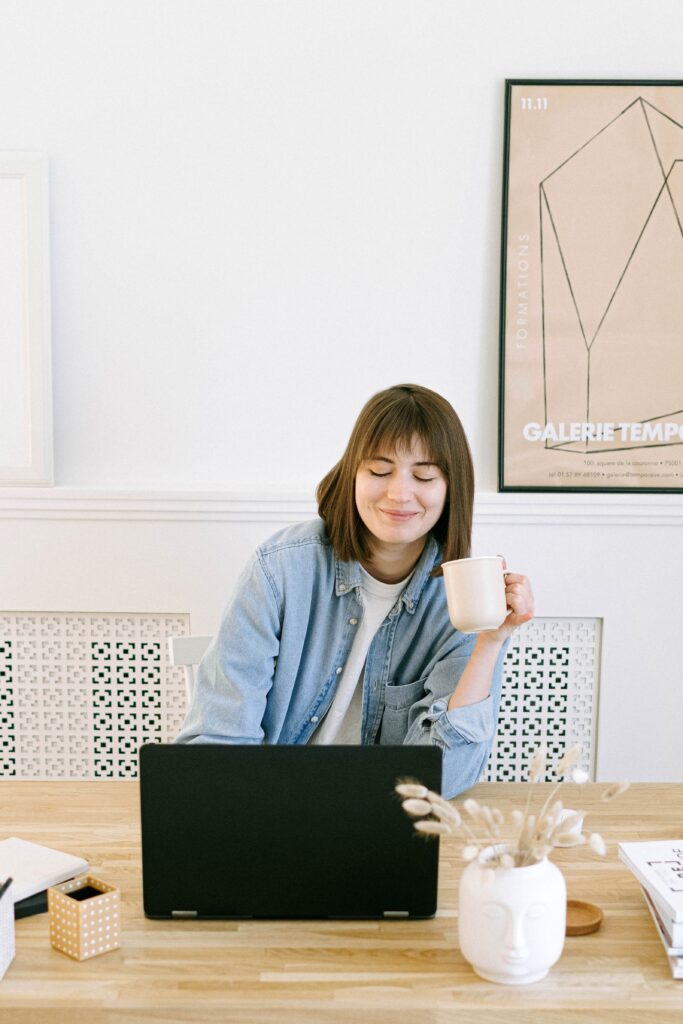 Woman Smiling Drinking Coffee Looking At Computer